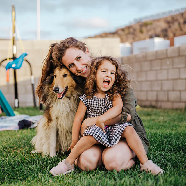 pies z długą sieścią w ogrodzie przytulający się razem z kobietą i dzieckiem