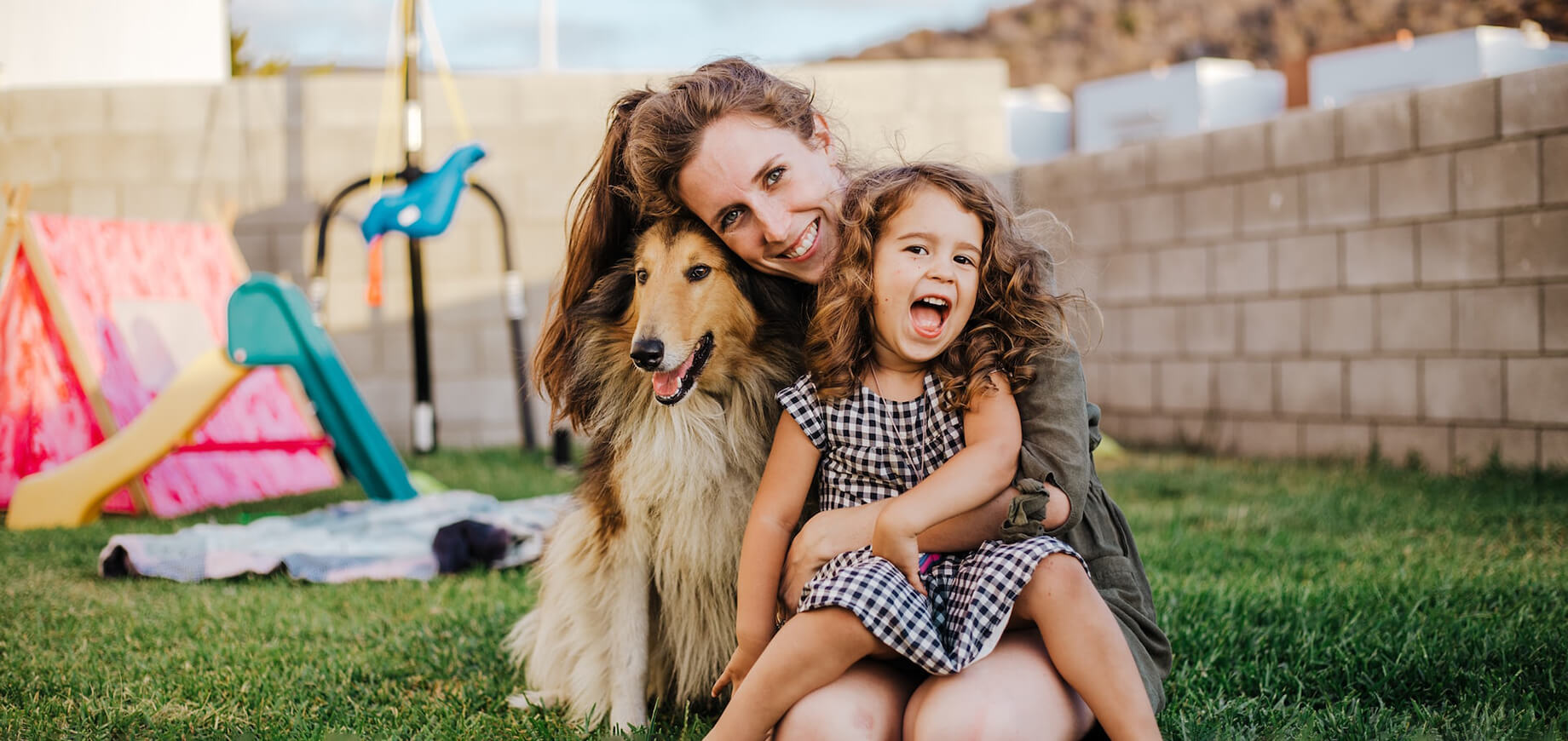 pies z długą sieścią w ogrodzie przytulający się razem z kobietą i dzieckiem