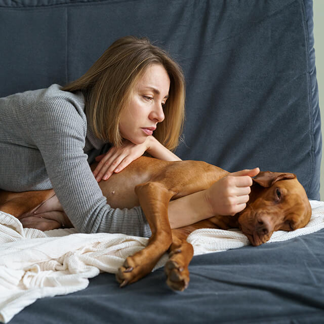 kobieta z blond włosami leżąca na kanapie z psem